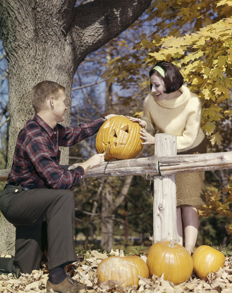 Detail of 1960s Young Couple Man Woman In Autumn Woods Carving Halloween Jack-O-Lantern Pumpkin by Corbis