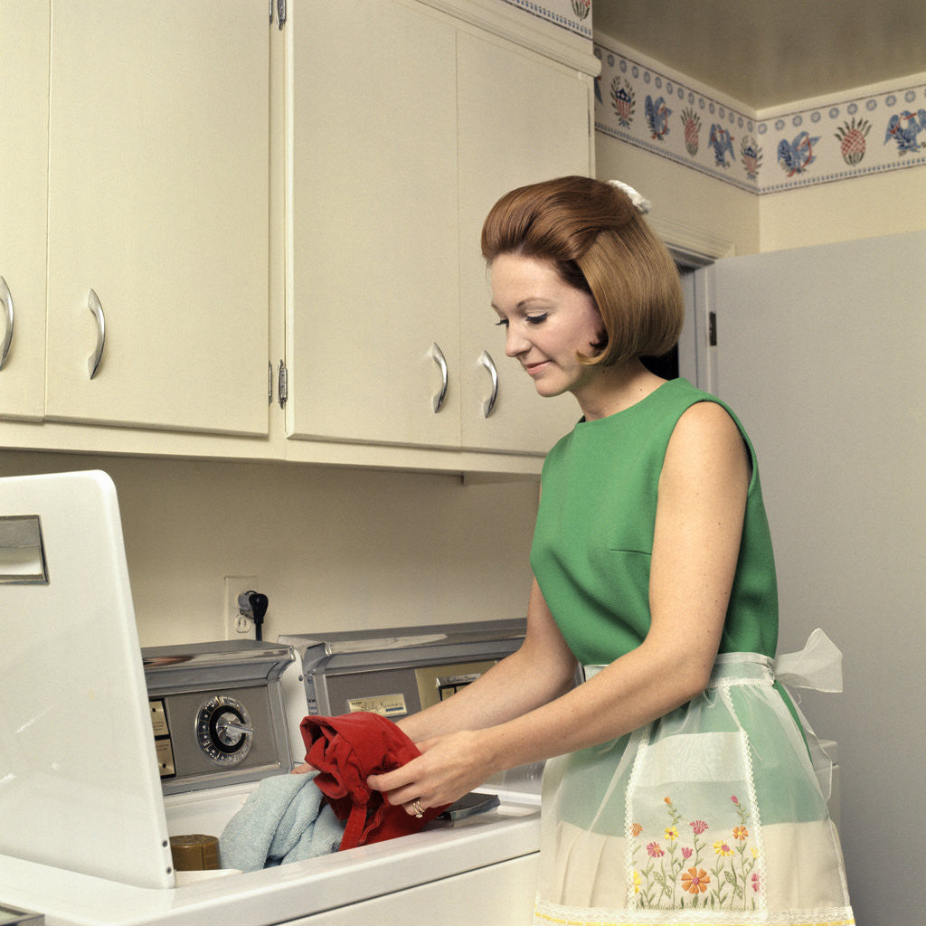 Detail of 1970s Woman Housewife Homemaker Wearing Apron Loading Laundry Into Washing Machine by Anonymous