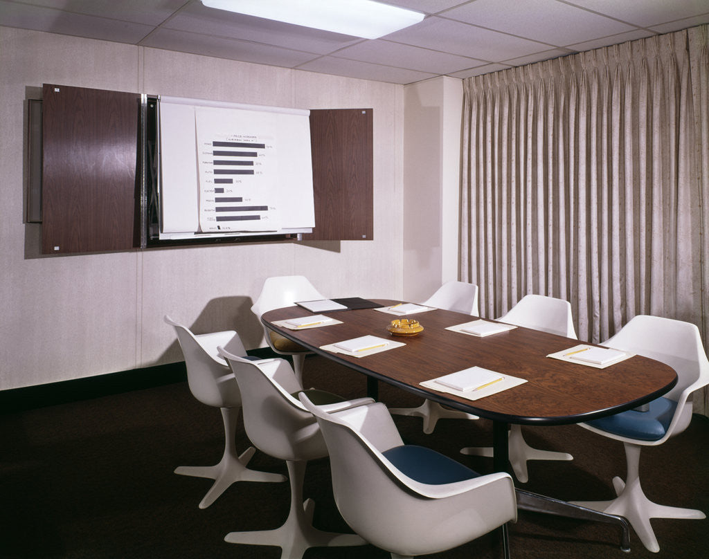 Detail of 1960s Office Conference Room With Table Chairs Writing Pads Ashtray And Wall Chart by Anonymous