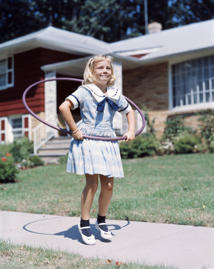 Detail of 1950s 1960s Young Girl Playing With Hula Hoop Outside On Suburban Sidewalk In Sailor Style Dress by Anonymous