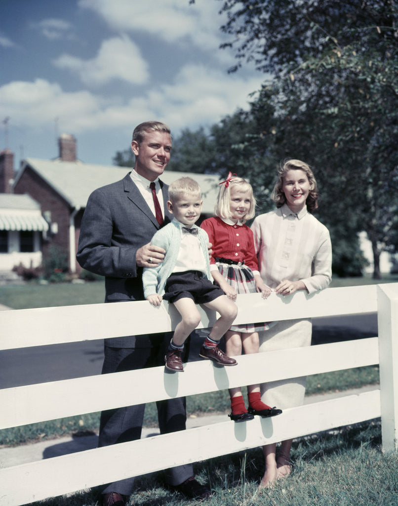 Detail of 1950s 1960s Family Portrait Mother Father Daughter Son At White Fence Of Suburban Home by Corbis