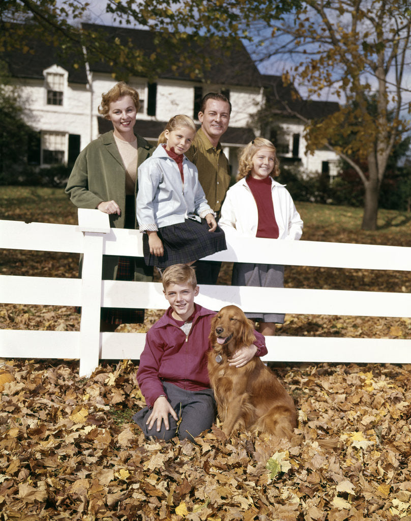 Detail of 1960s Family with Dog At White Board Fence In Front Of Colonial Style Suburban House by Corbis