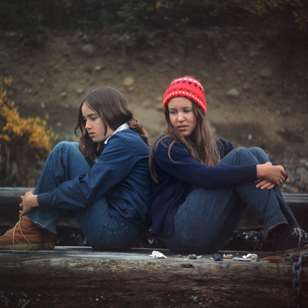 Detail of 1970s Two Sad Serious Teenage Girls Sitting Back To Back Outside by Anonymous