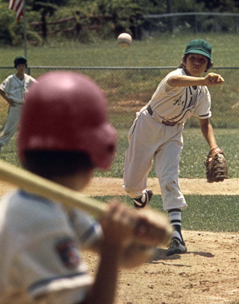 Detail of 1970s Little League Baseball Game Boy Pitcher Throwing Ball To Batter by Corbis