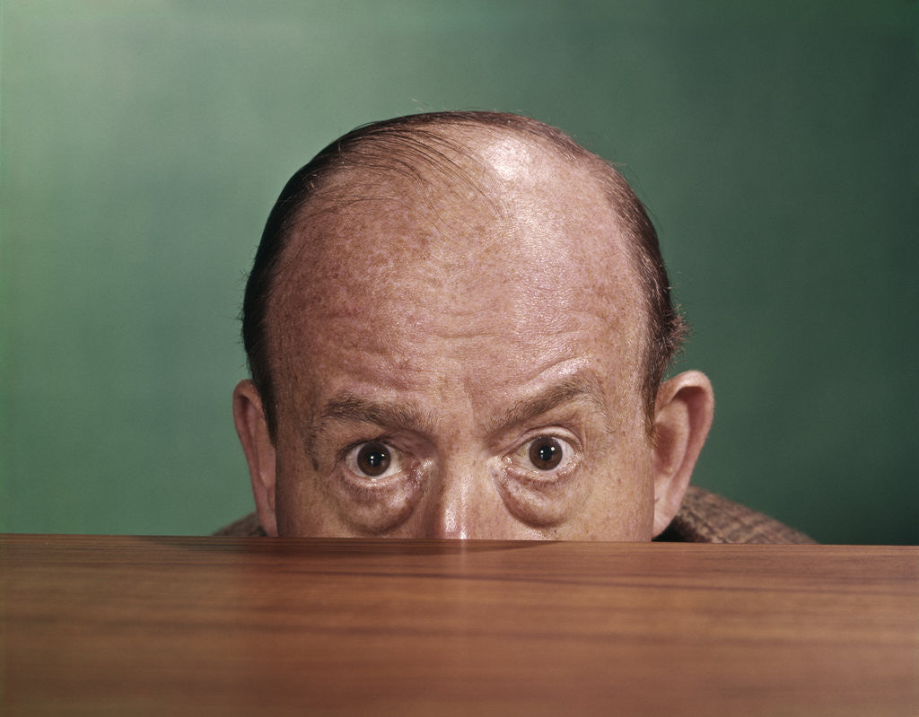 Detail of 1960s Balding Man Peeking Over Desktop With Only Top Half Of Head Showing by Anonymous