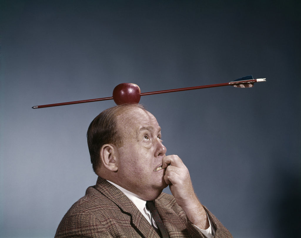Detail of 1960s Anxious Business Man Biting Finger With Nails Arrow Shot Through Apple On Of His Top Head by Corbis