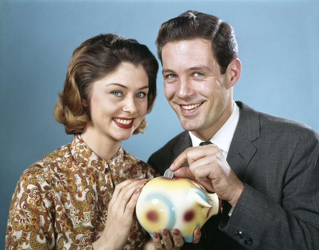 Detail of 1950s 1960s Young Couple Man And Woman Put Quarter In Savings Piggy Bank by Corbis