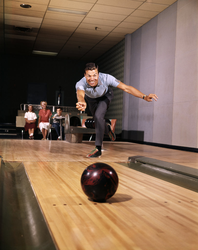 Detail of 1960s Man In Good Form Releasing Bowling Ball Down Lane Wife Woman 2 Kids Behind Him by Anonymous