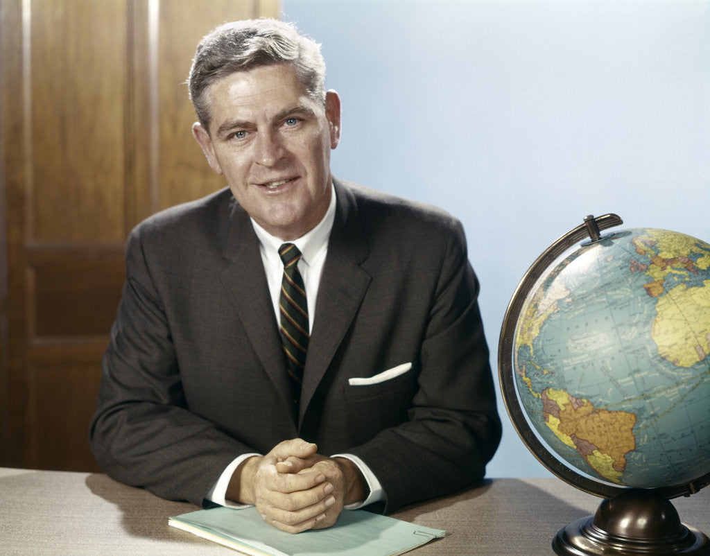Detail of 1960s Portrait Man Businessman Sitting At Desk Next To Globe Of The Earth by Anonymous