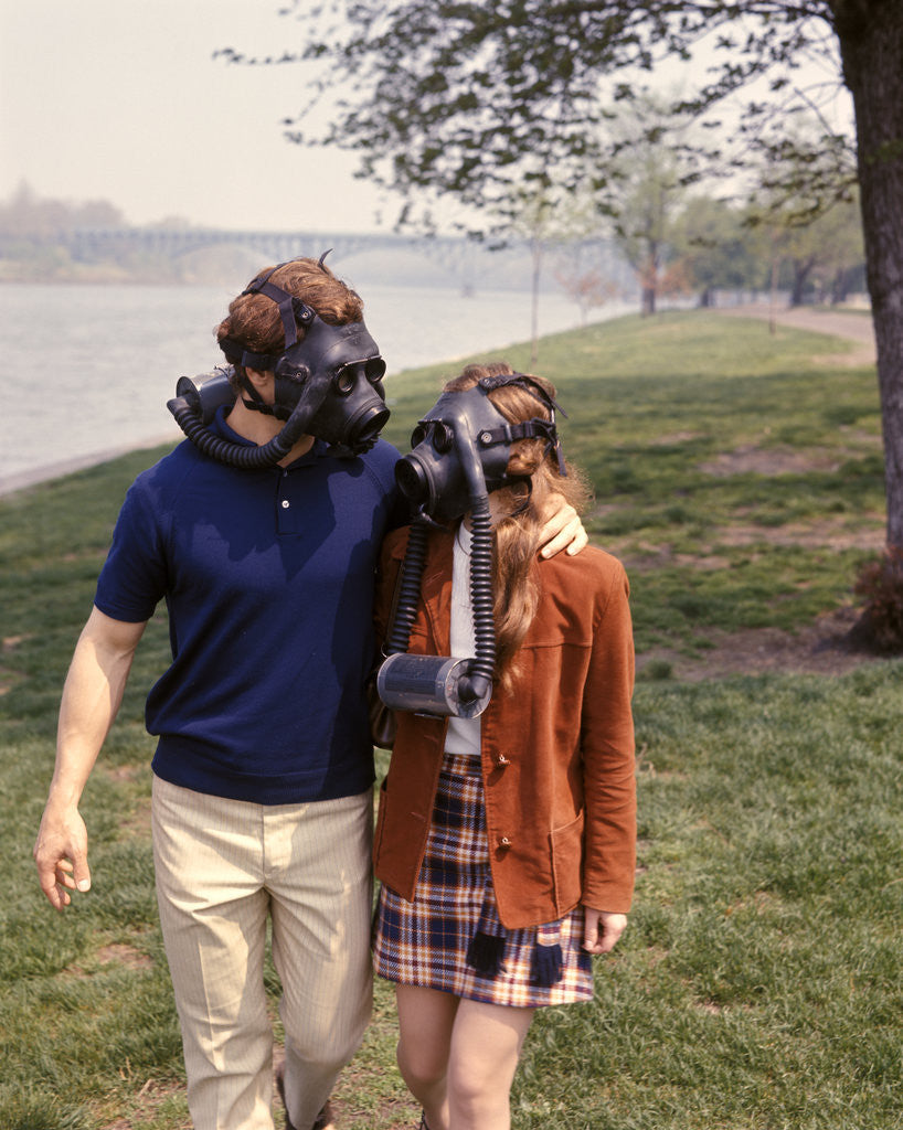 Detail of 1970s Young Romantic Teenage Couple Man Woman Wearing Gas Masks Walking By River by Anonymous