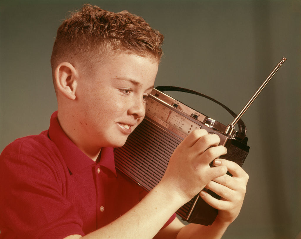 1960s Young Red Hair Pre-Teen Boy Listening To Portable Transistor