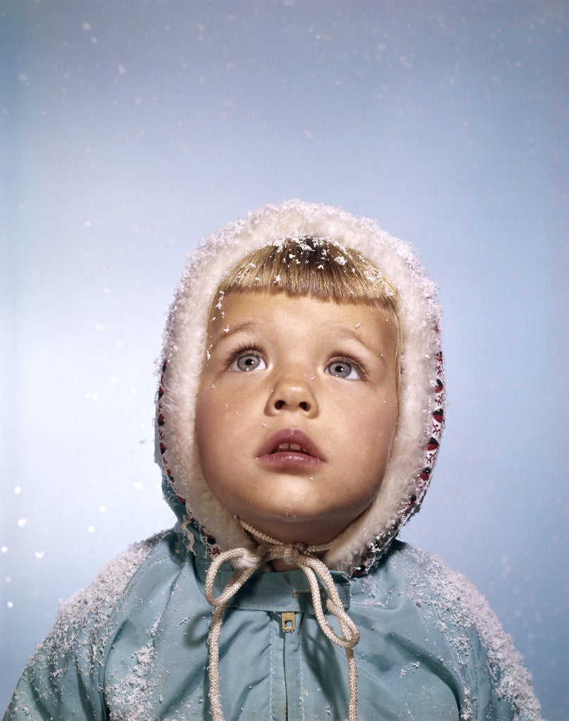 Detail of 1960s Cold Little Girl In Winter Coat And Hood Looking Up At Falling Snow by Anonymous