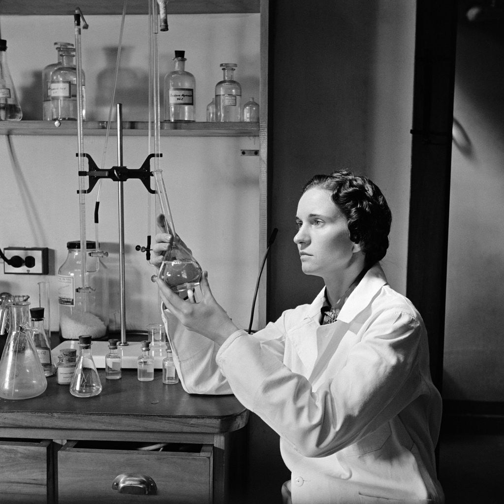 Detail of 1930s 1940s Woman Scientist In Lab Coat Holding Up And Examining Beaker Of Liquid by Anonymous