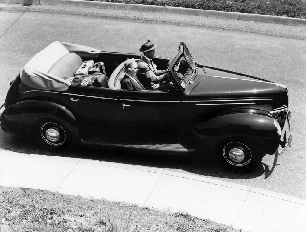 Detail of 1930s 1940s Couple Driving 1938 Convertible Four Door Sedan Automobile With Luggage In Back Seat by Anonymous