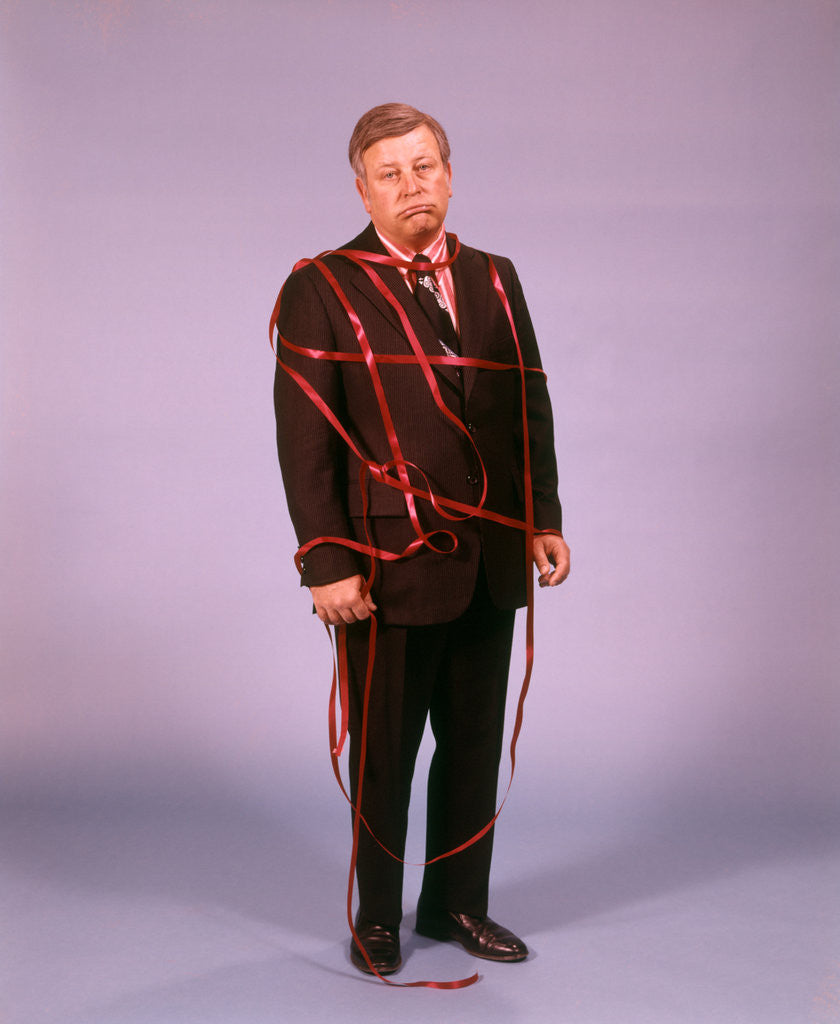 Detail of 1970s Middle Aged Man Business Suit Disapointed Depressed Unhappy Tied Up In Red Tape by Anonymous