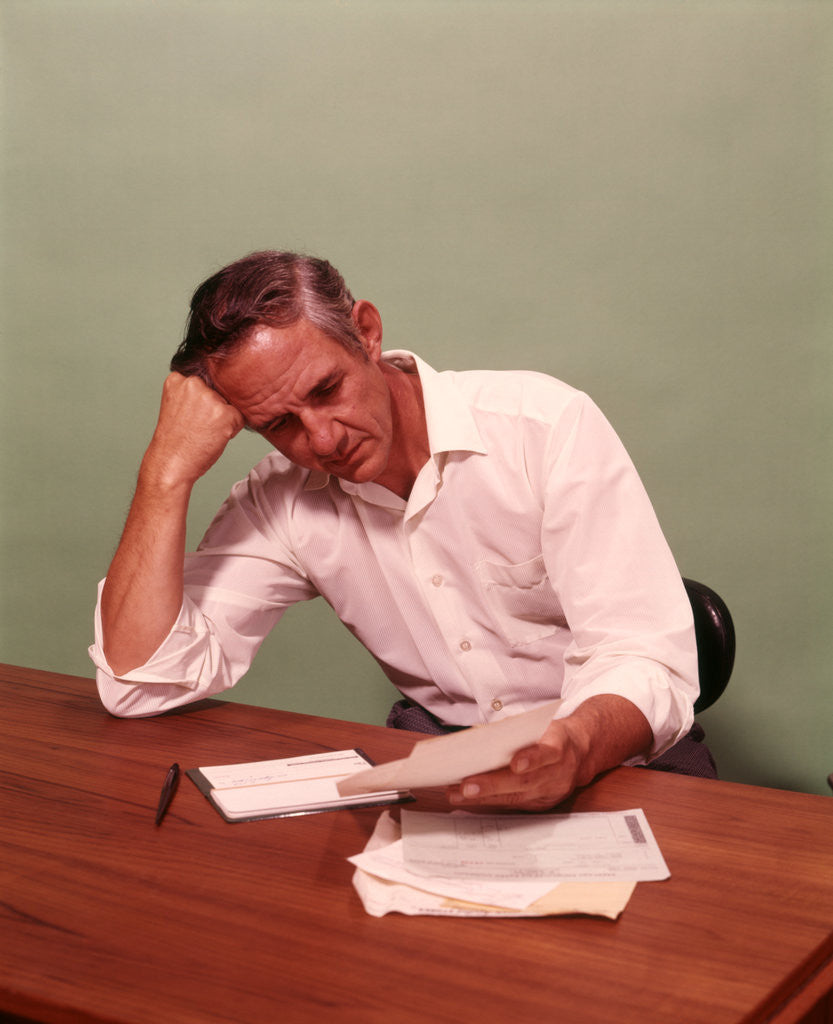 Detail of 1970s Middle Age Man Sitting At Desk Worried About Bills To Pay by Anonymous