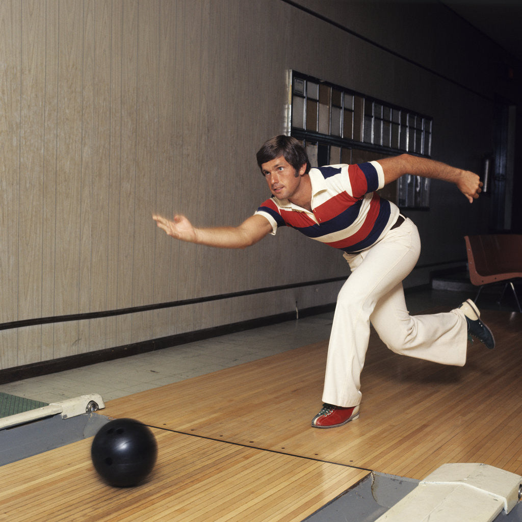 Detail of 1970s Man Stripe Shirt Flare Leg Pants Throwing Bowling Ball Down Lane Alley by Corbis
