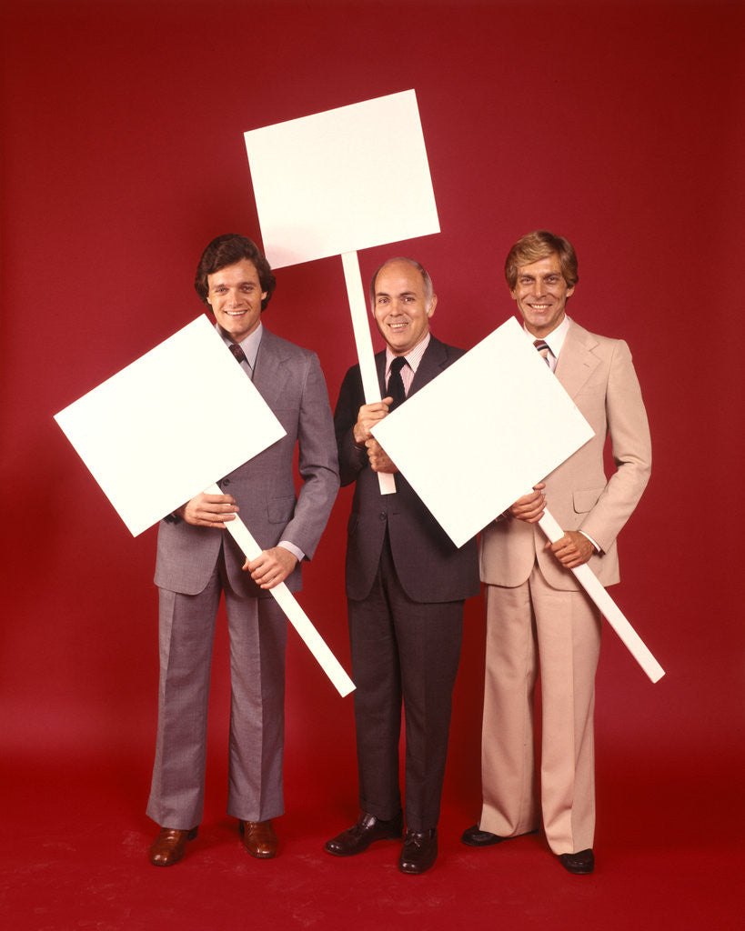 Detail of 1970s Three Business Men Wearing Suits Each Carrying Blank Sign Placard Red Background by Corbis