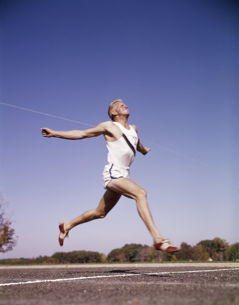 Detail of 1960s Runner At Finish Line Breaking Through Tape by Corbis