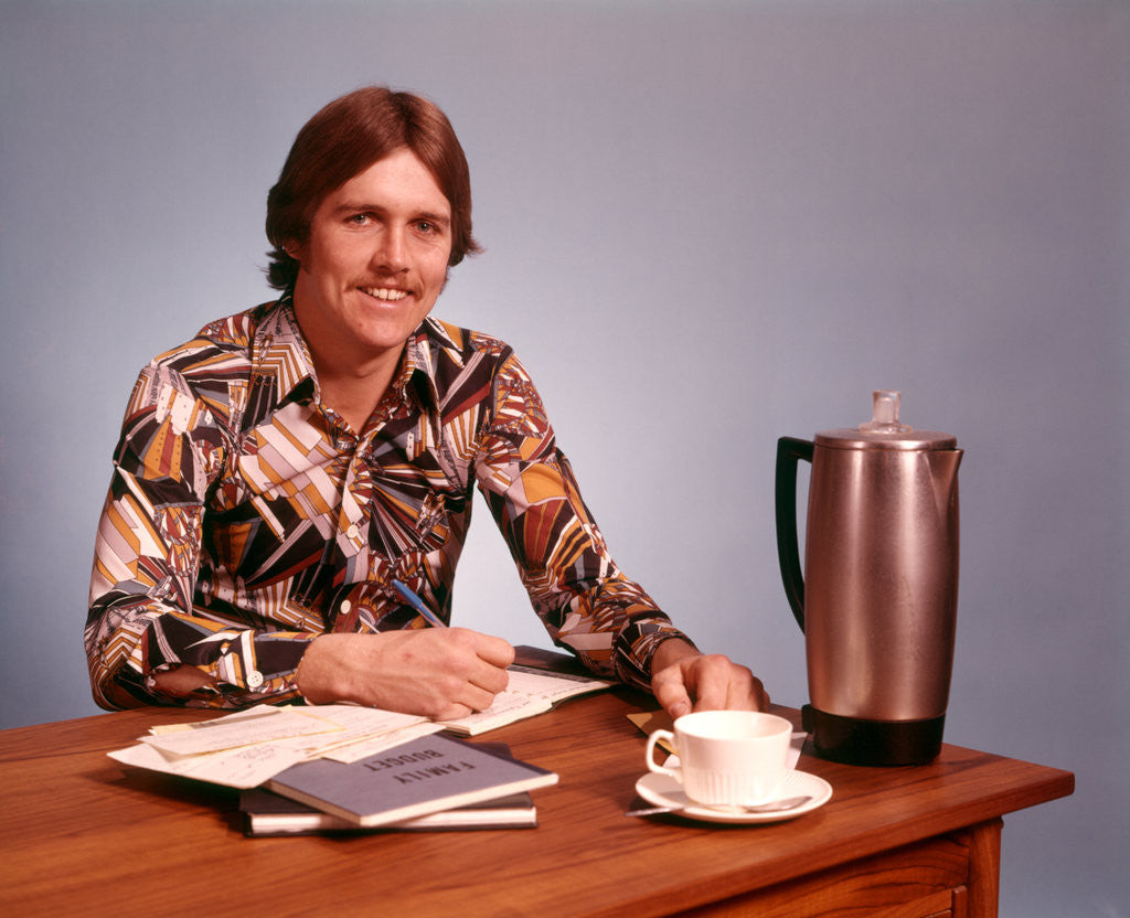 Detail of 1970s Young Man Mustache Loud Print Shirt Desk Empty Coffee Cup Pot Family Budget by Anonymous