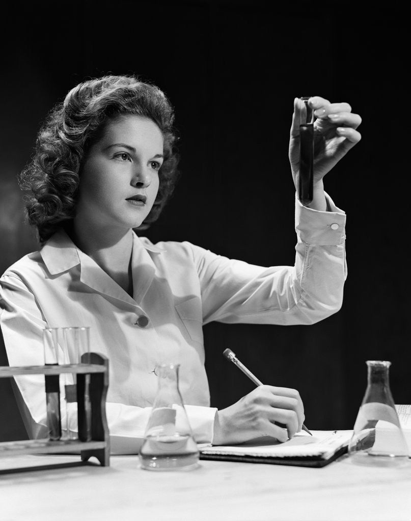Detail of 1940s Student Nurse Holding Up Test Tube While Taking Notes In Science Class by Anonymous