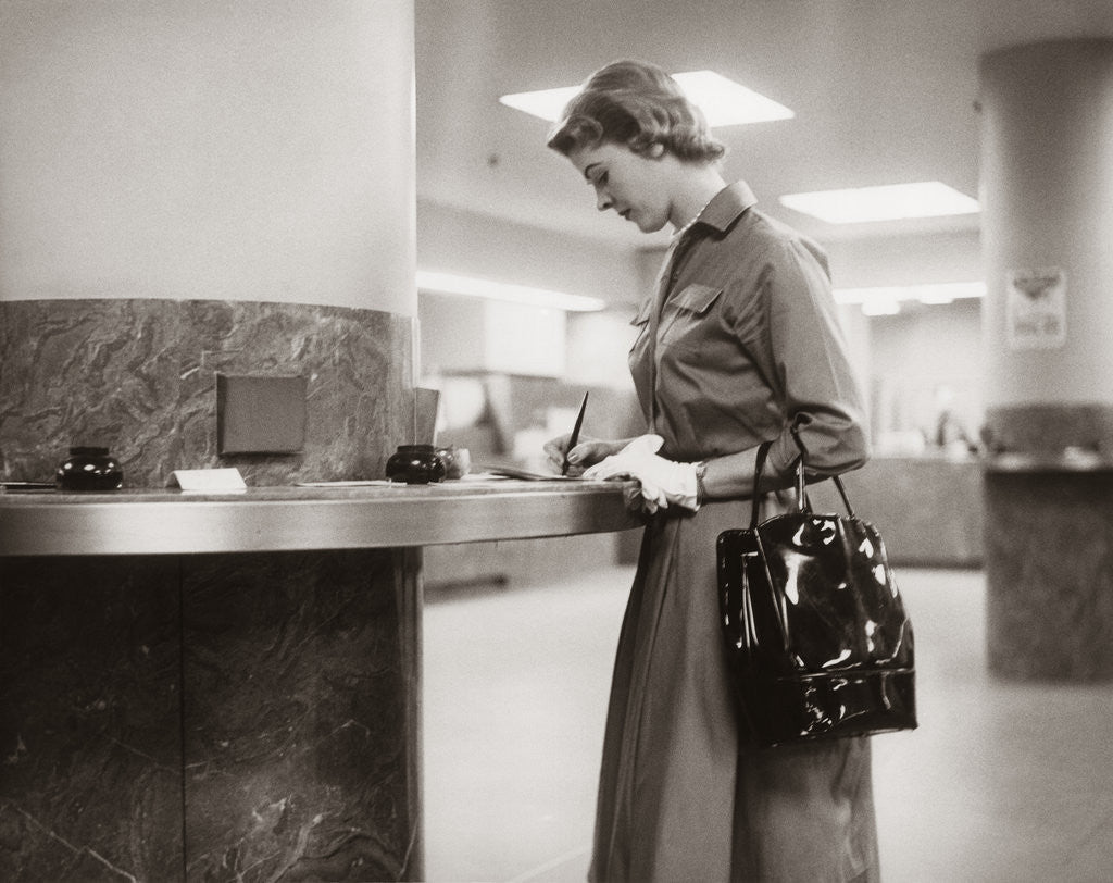 Detail of 1950s 1960s Woman Handbag On Arm Gloves Filling Out Deposit Slip Bank Counter by Anonymous
