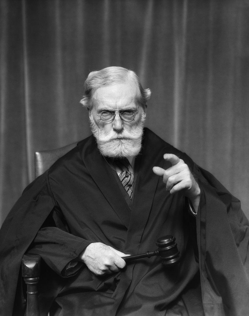 Detail of 1930s Stern Elderly Judge With Beard And Glasses Pointing At Camera by Anonymous