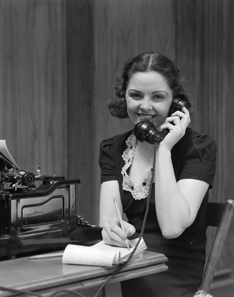 Detail of 1930s Woman Receptionist Secretary Sitting At Desk In Office Talking On Telephone by Corbis