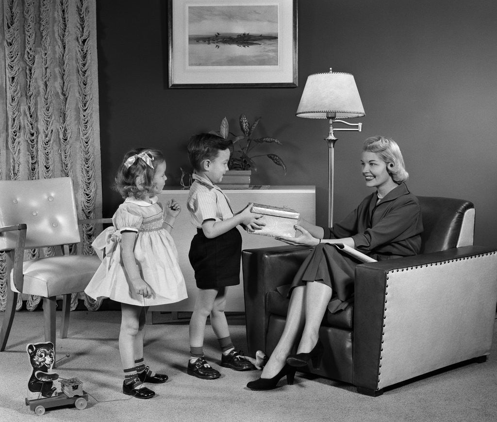 Detail of 1950s Little Boy And Girl Son And Daughter Giving Woman Mother Sitting In Living Room A Gift Present by Corbis