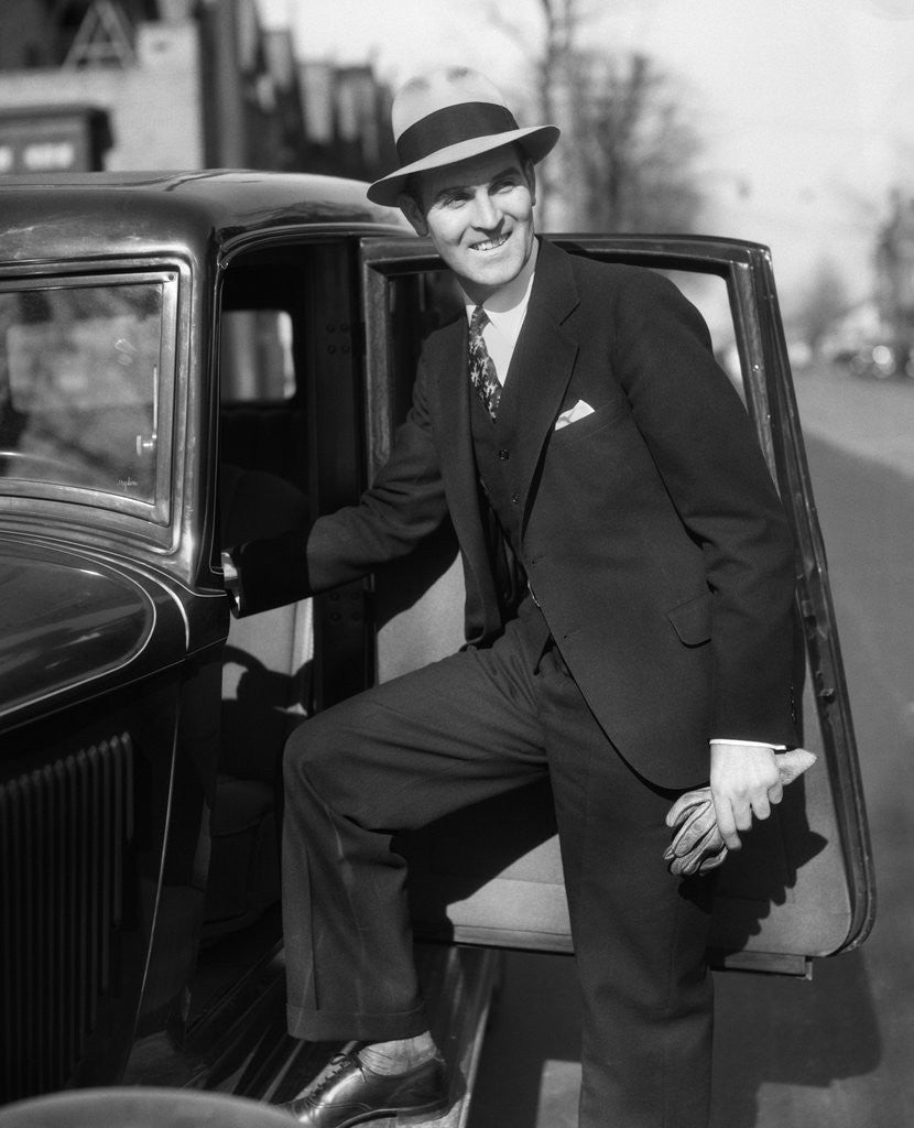 Detail of 1930s Man In Suit And Hat Holding Gloves Stepping Into Automobile Driver Seat by Anonymous