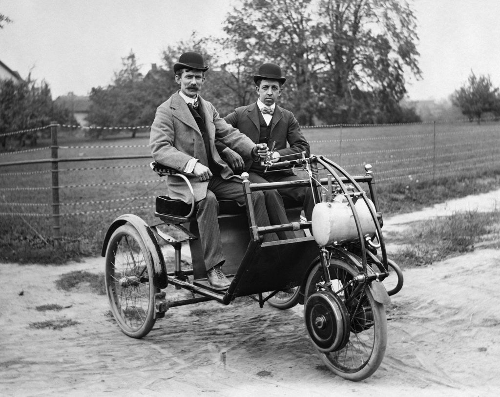 Detail of 1900s Two Men In Bowler Hats Sitting In Three Wheel Motorized Horseless Carriage by Corbis