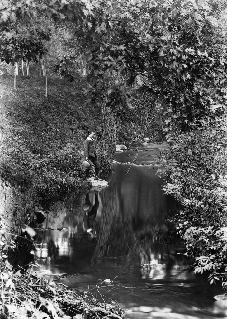 Detail of 1890s 1900 Boy Standing In Wooded Area Looking Down At Reflection In Creek by Corbis