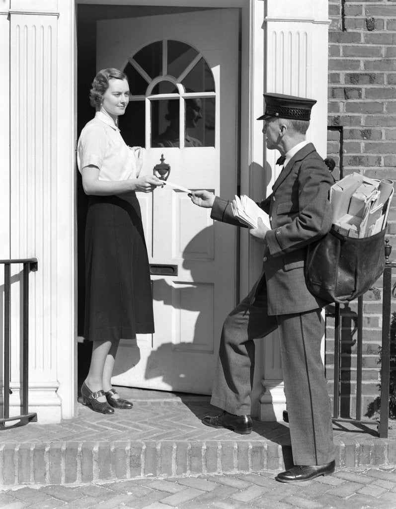 Detail of 1930s Postman Giving A Letter To A Woman In The Doorway Of A Colonial Brick Home by Corbis