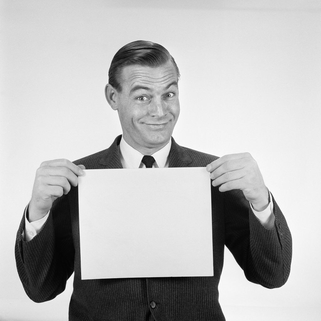 Detail of 1950s 1960s Man Funny Facial Expression Holding Up Blank Empty Sheet Paper Placard Sign by Corbis