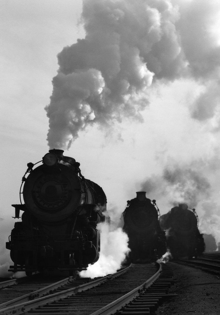 Detail of 1930s 1940s Head-On View Of Three Steam Engines Silhouetted Against Billowing Smoke And Steam Outdoor by Corbis