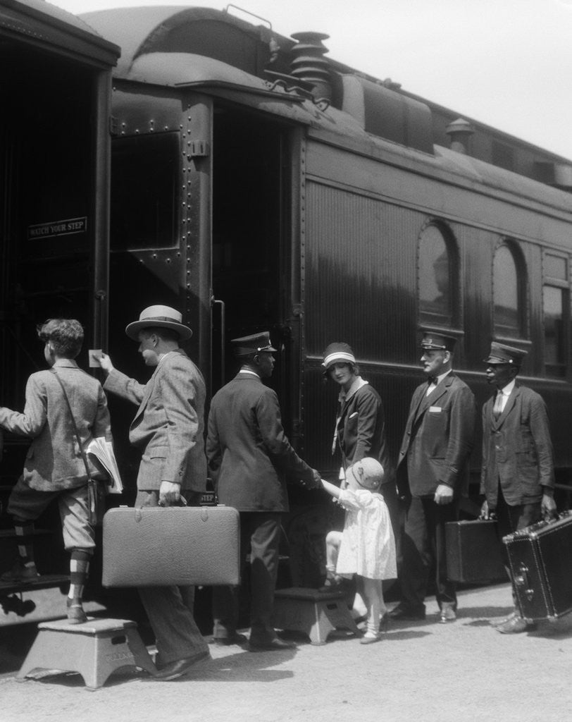 Detail of 1920s Family Boarding Passenger Train Assisted By Trainman And Porters Carrying Luggage Outdoor by Corbis