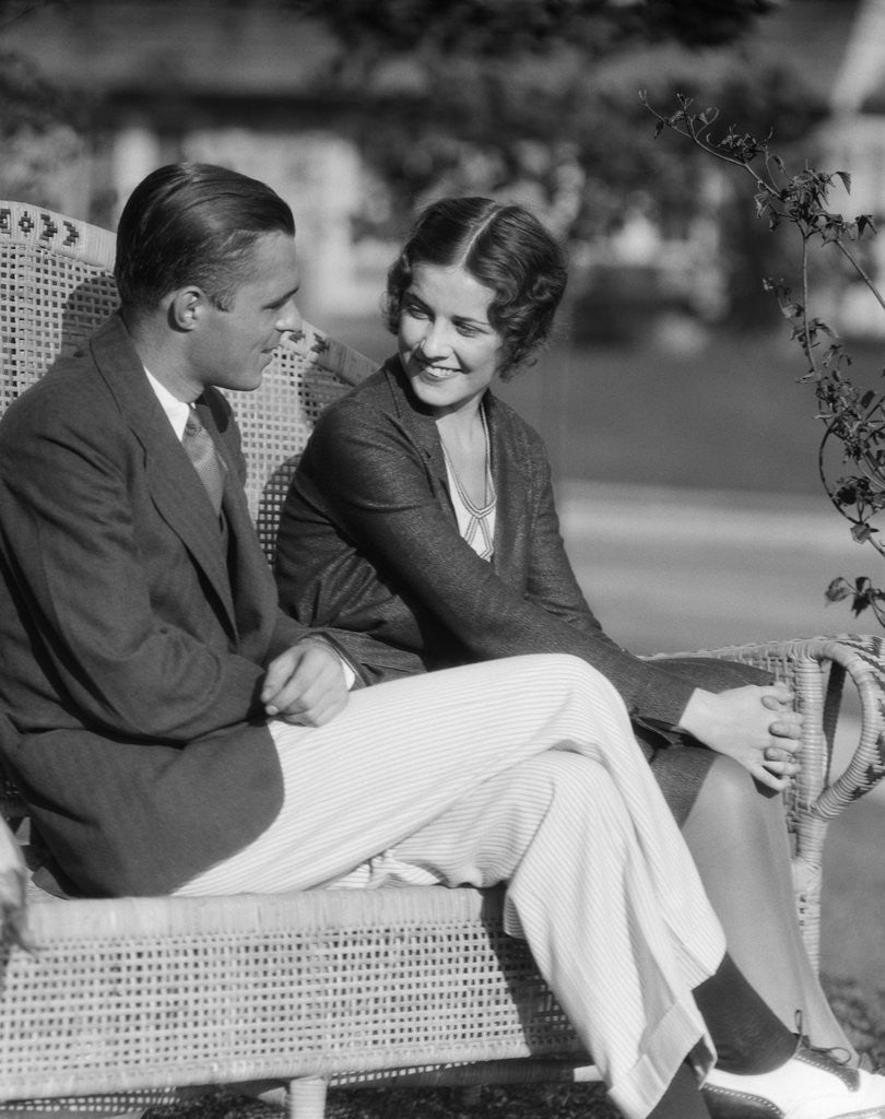 Detail of 1930s Couple Sitting Together On Wicker Bench Husband Wife Outdoor by Corbis