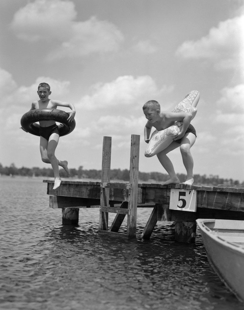 Detail of 1940s 1950s Two Boys Wearing Inflatable Inner Tubes About To Jump In Lake Off Pier by Corbis