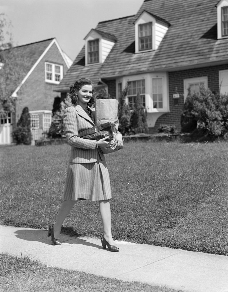 Detail of 1940s Woman Walking Shopping Carrying Grocery Bag On Suburban House Sidewalk by Anonymous