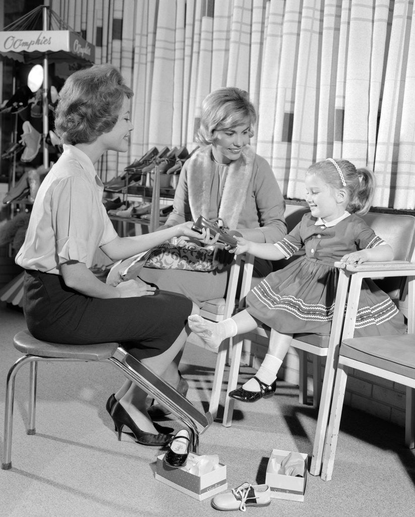 Detail of 1960s Mother Daughter Shoe Shopping Saleswoman Showing Patent Leather Shoe To Girl by Anonymous