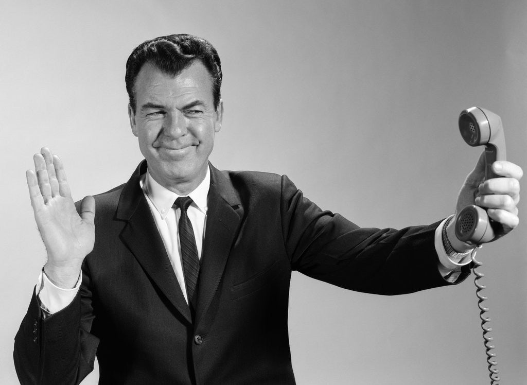 Detail of 1960s Businessman Holding Telephone At Arms Length With Expression Of Disgust Or Rejection by Anonymous