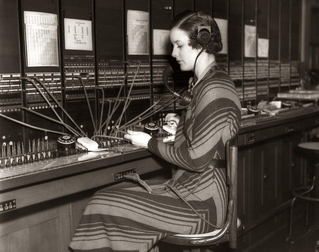 Detail of 1930s Woman Telephone Operator Sitting At Large Manual Switchboard Directing Calls by Anonymous