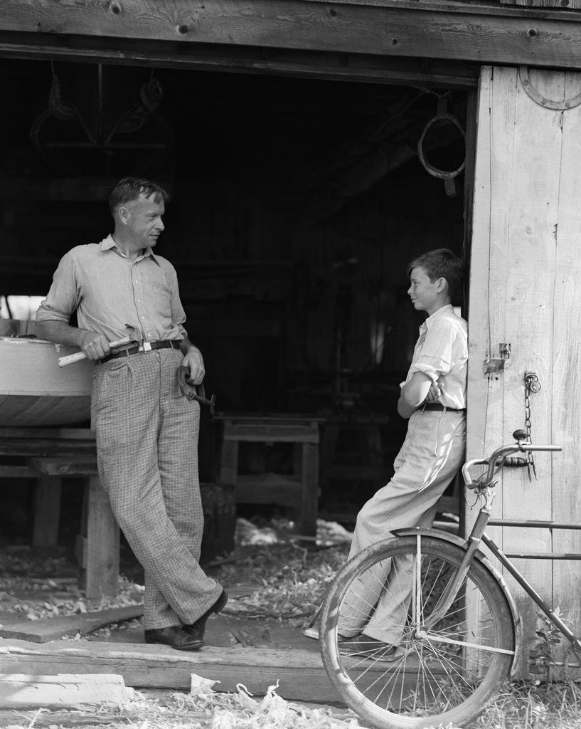 Detail of 1930s Man Father Holding Hand Tools Talking To Boy Son Leaning In Doorway Of Boat Shed by Anonymous
