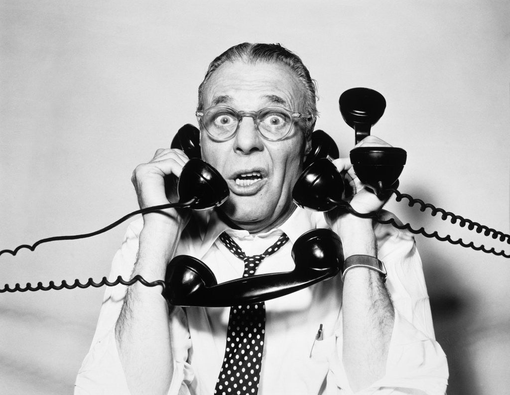 Detail of 1950s 1960s Portrait Of Frazzled Businessman Trying To Answer Four Black Telephones Phones At Once by Anonymous