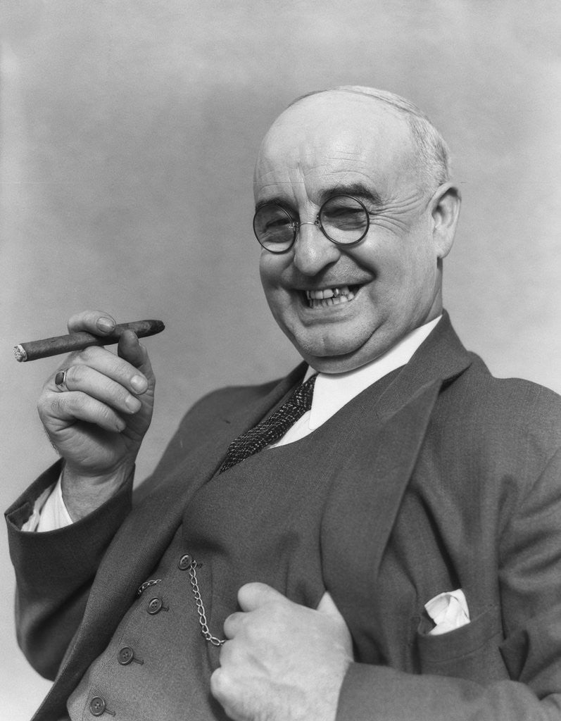Detail of 1930s Elderly Businessman In 3-Piece Suit and Glasses Leaning Back With Cigar In Hand by Corbis