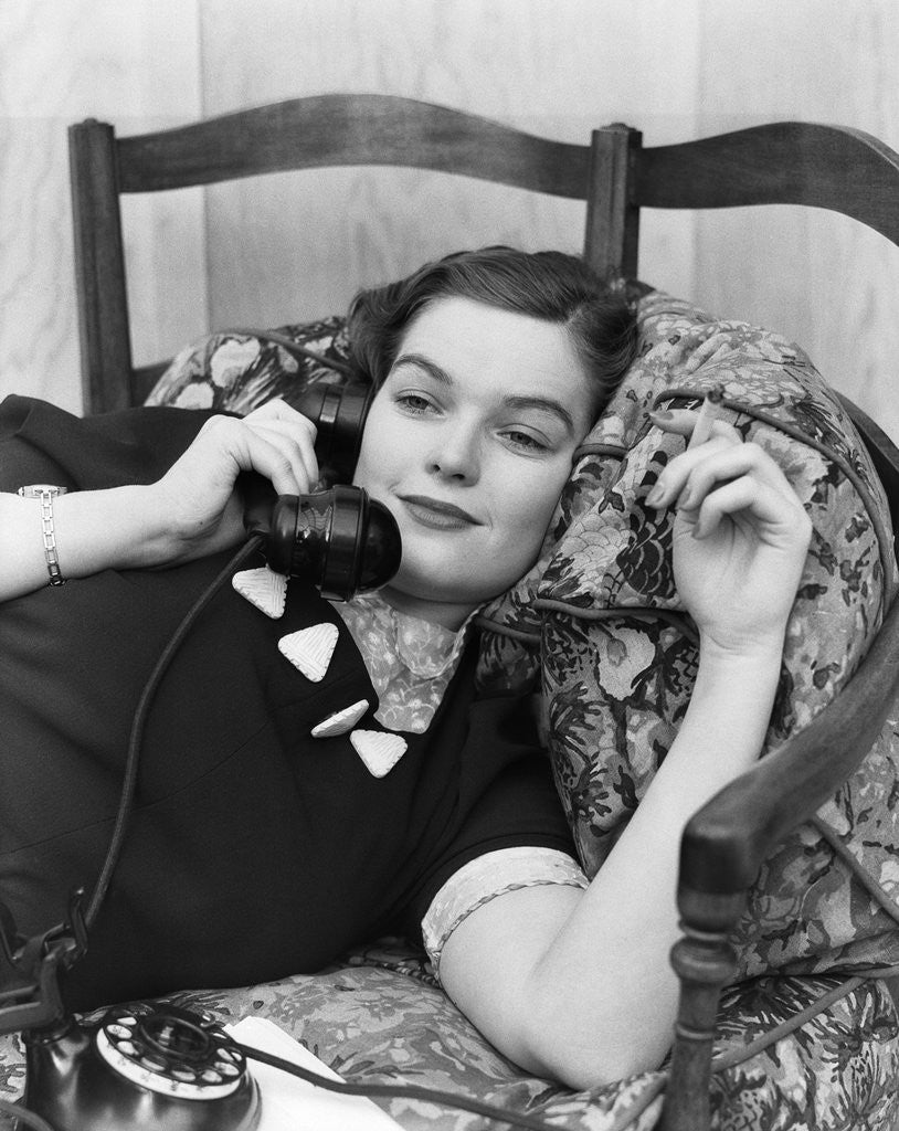 Detail of 1930s Young Brunette Woman Reclining On Pillows Cigarette In Hand Talking On Telephone by Corbis