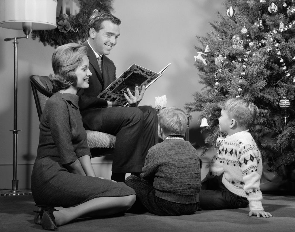 Detail of 1960s Family Father Mother Two Sons Sitting By Christmas Tree In Living Room Reading A Book by Anonymous