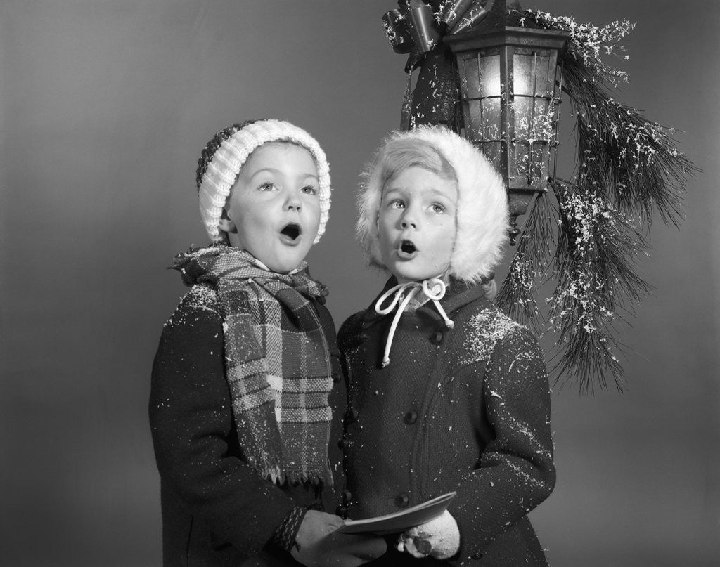 Detail of 1960s Boy And Girl Singing Christmas Carol Together Under Snowy Outdoor Porch Light by Corbis
