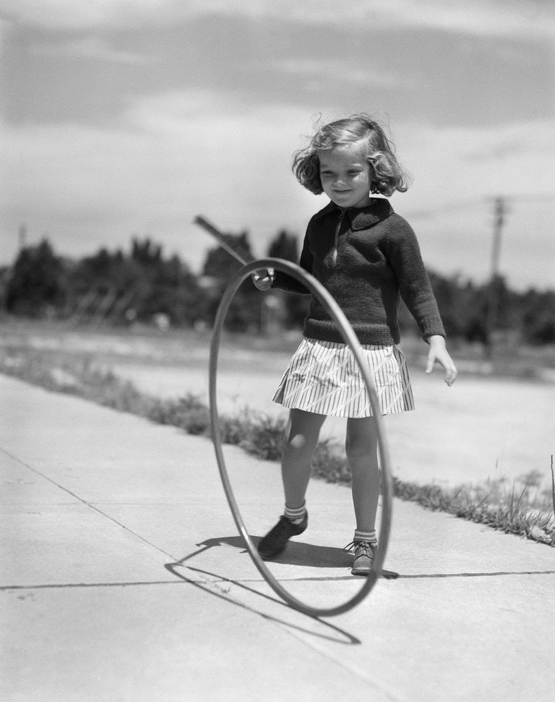 Detail of 1930s Girl Playing With Hoop And Stick On Sidewalk by Corbis