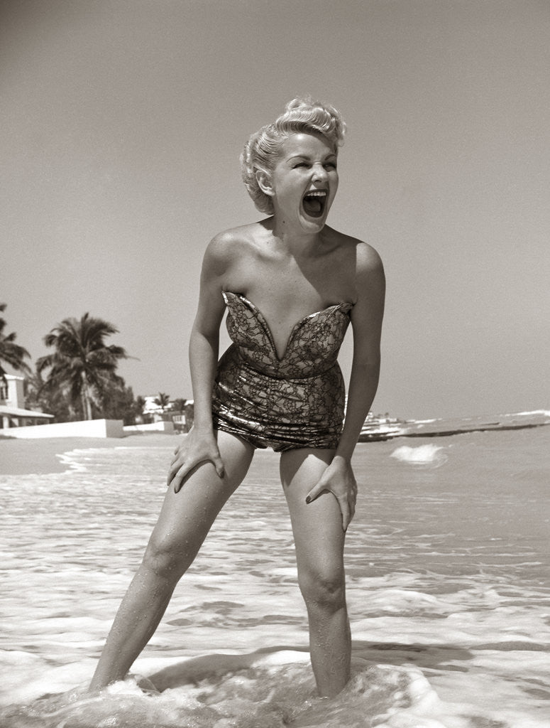 Detail of 1950s Laughing Woman In Strapless Low Cut Bathing Suit Swim Wear Wading Up To Ankles In Surf by Corbis